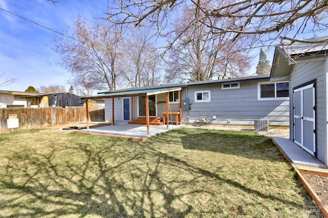 rear view of house with entry steps, a patio, a yard, and fence