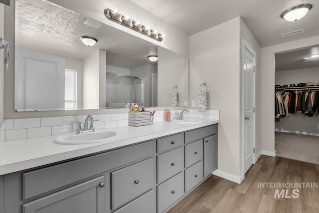 1266 S Wiston Ave, Kuna, ID 83634 - bathroom featuring double vanity, wood finished floors, an enclosed shower, a spacious closet, and baseboards