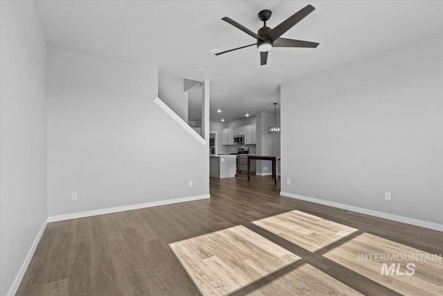 8450 S Bogus Ridge Ave, Boise, ID 83716 - unfurnished living room with dark wood-type flooring, ceiling fan, baseboards, and stairway