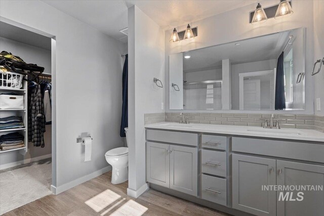 8450 S Bogus Ridge Ave, Boise, ID 83716 - bathroom featuring double vanity, wood finished floors, tasteful backsplash, and toilet