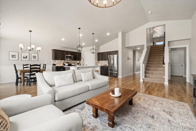 2188 Navigator St, Middleton, ID 83644 - living room with a chandelier, stairs, vaulted ceiling, light wood-style flooring, and recessed lighting