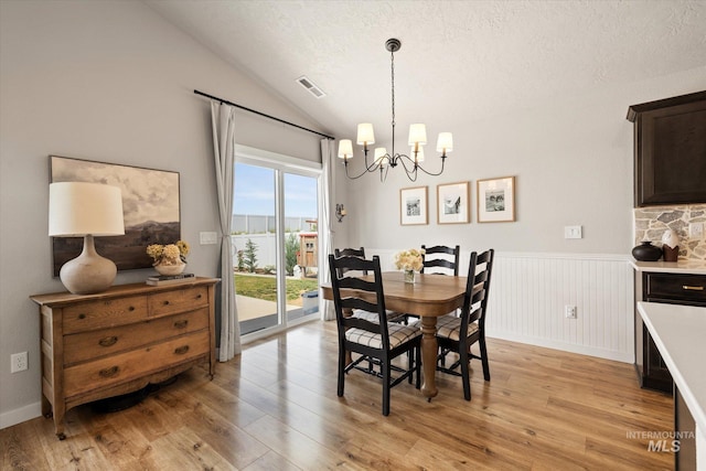 2188 Navigator St, Middleton, ID 83644 - dining room featuring a chandelier, light wood-type flooring, lofted ceiling, a wainscoted wall, and a textured ceiling