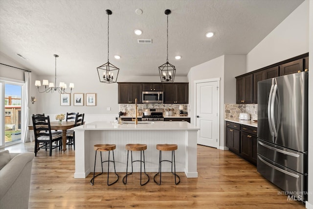 2188 Navigator St, Middleton, ID 83644 - kitchen featuring stainless steel appliances, a textured ceiling, light countertops, decorative backsplash, and a chandelier