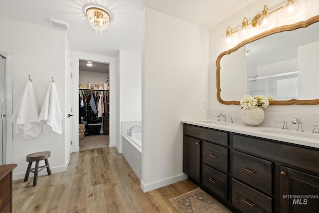 2188 Navigator St, Middleton, ID 83644 - bathroom with double vanity, wood finished floors, a chandelier, a bath, and a walk in closet