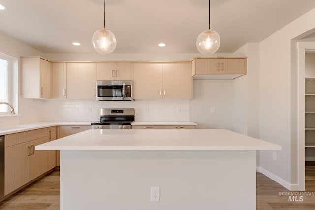 kitchen with appliances with stainless steel finishes, decorative backsplash, a sink, and light countertops