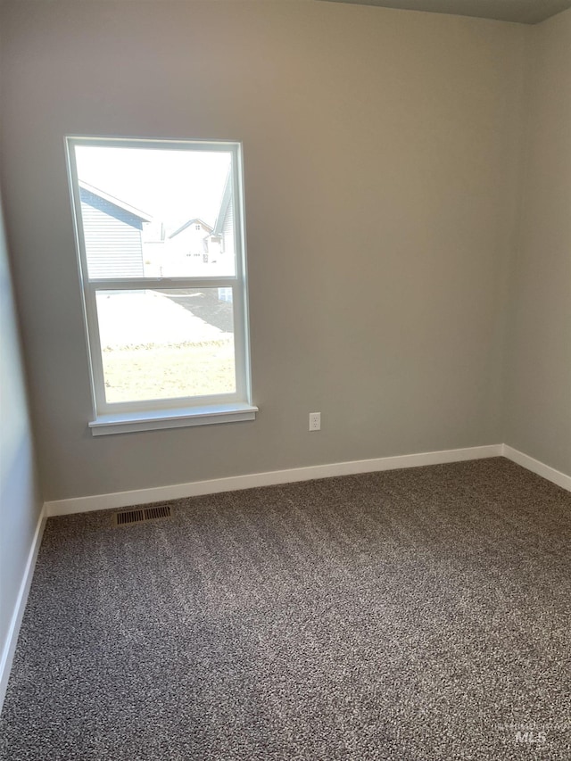 carpeted spare room featuring baseboards and visible vents