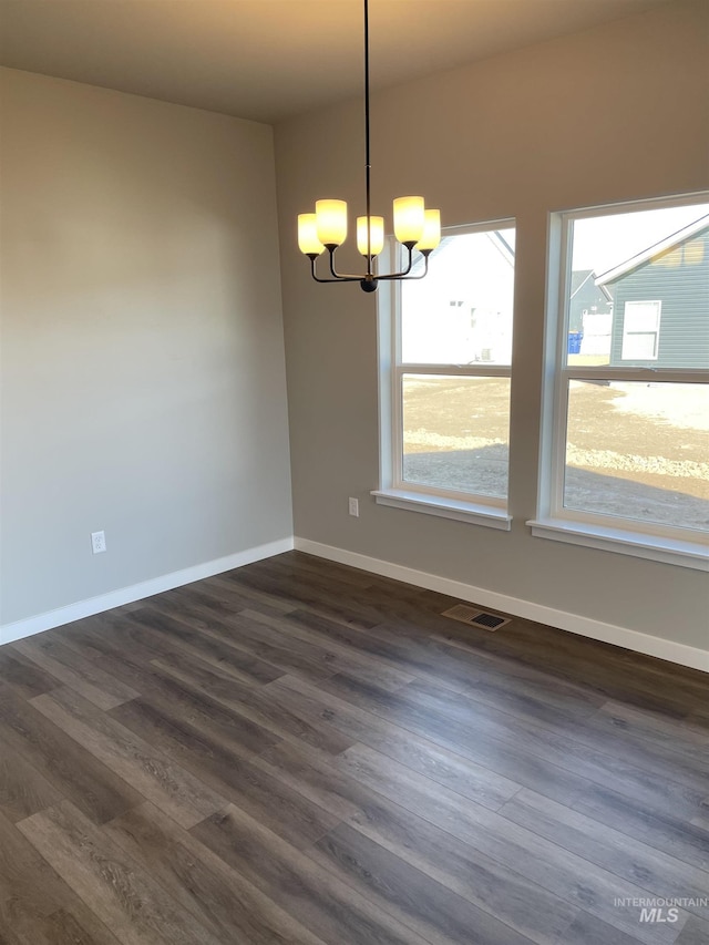 unfurnished room with dark wood finished floors, an inviting chandelier, baseboards, and visible vents