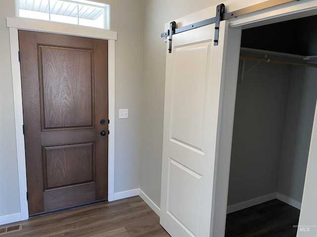 entryway with dark wood finished floors, visible vents, a barn door, and baseboards