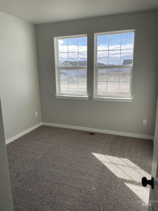 carpeted spare room featuring baseboards