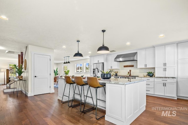 kitchen featuring recessed lighting, white cabinets, plenty of natural light, and wall chimney exhaust hood
