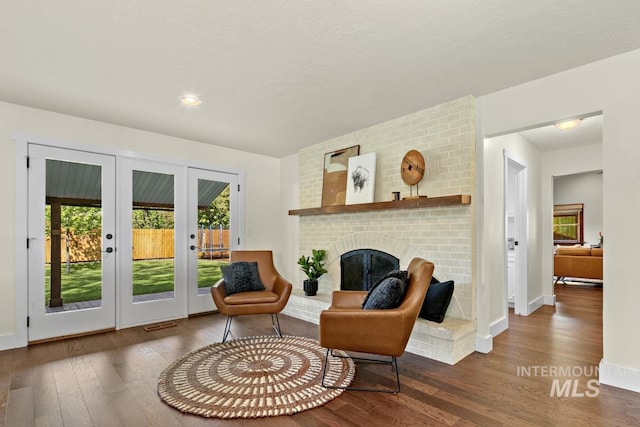 sitting room featuring baseboards, french doors, a fireplace, and wood-type flooring