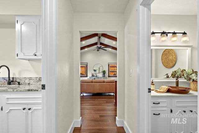 corridor with vaulted ceiling with beams, a sink, and dark wood-type flooring