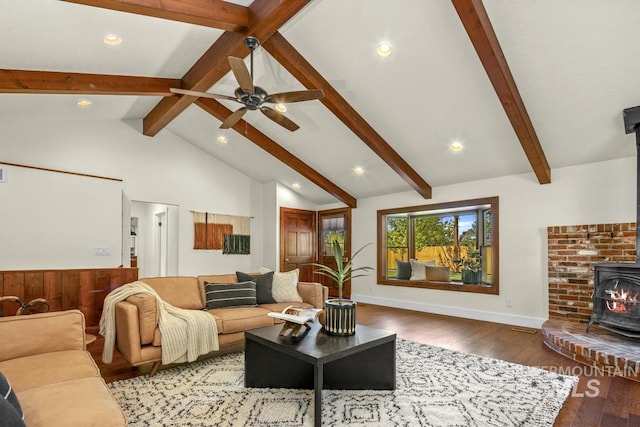 living room with wood finished floors, a wood stove, recessed lighting, ceiling fan, and vaulted ceiling with beams