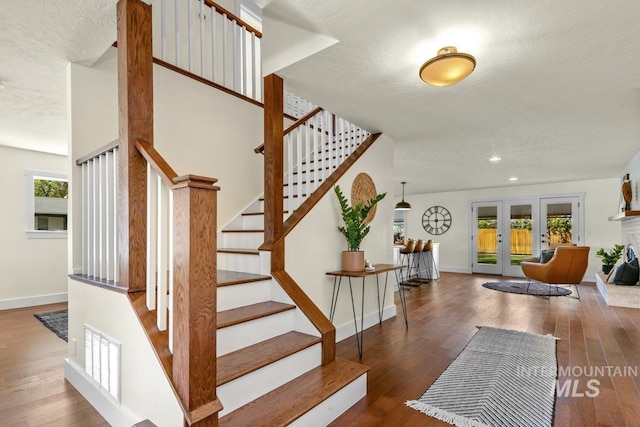 staircase with baseboards, visible vents, and wood finished floors