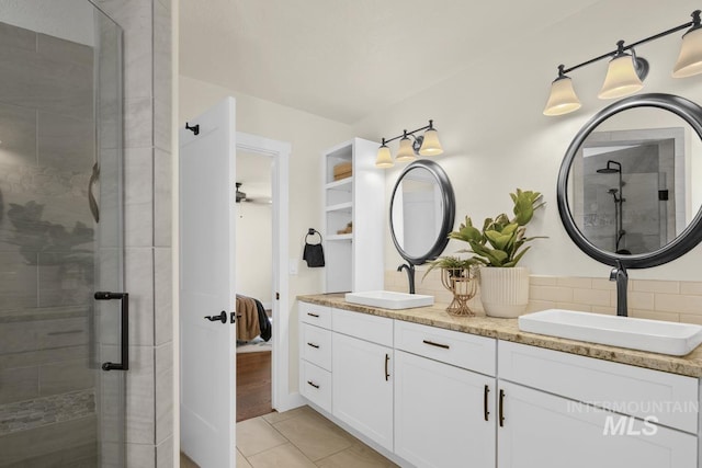 full bathroom featuring double vanity, tile patterned floors, a stall shower, and a sink