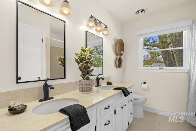 bathroom with a sink, toilet, visible vents, tile patterned floors, and double vanity