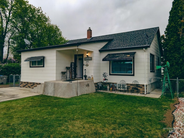 view of front of house with a chimney, a gate, fence, roof with shingles, and a front lawn