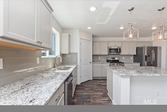 kitchen with appliances with stainless steel finishes, dark wood-type flooring, sink, pendant lighting, and a center island