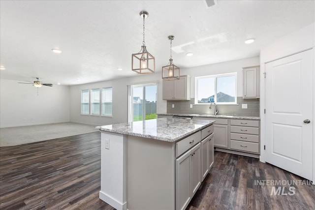 kitchen featuring gray cabinets, decorative light fixtures, a kitchen island, and dark wood-type flooring