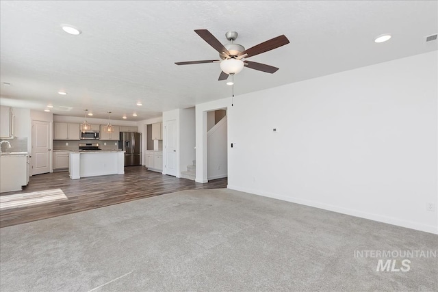 unfurnished living room featuring ceiling fan and hardwood / wood-style floors