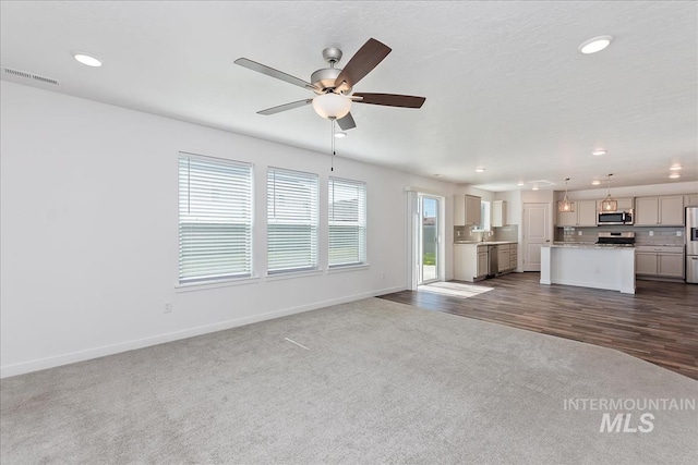 unfurnished living room featuring dark hardwood / wood-style floors, ceiling fan, and sink