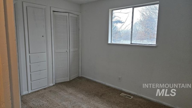 unfurnished bedroom with a closet, light colored carpet, and multiple windows