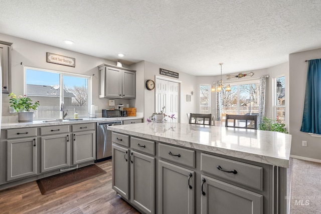 kitchen with a kitchen island, dishwasher, gray cabinets, an inviting chandelier, and a sink