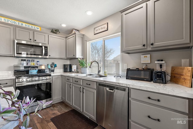 kitchen featuring a sink, gray cabinetry, light countertops, dark wood-type flooring, and stainless steel appliances