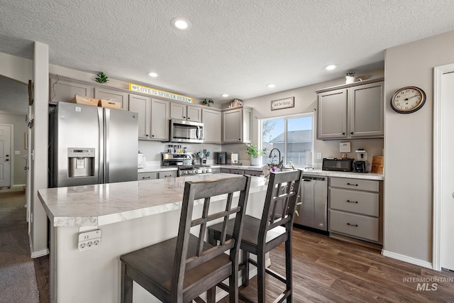 kitchen featuring gray cabinetry, stainless steel appliances, light countertops, and dark wood-type flooring