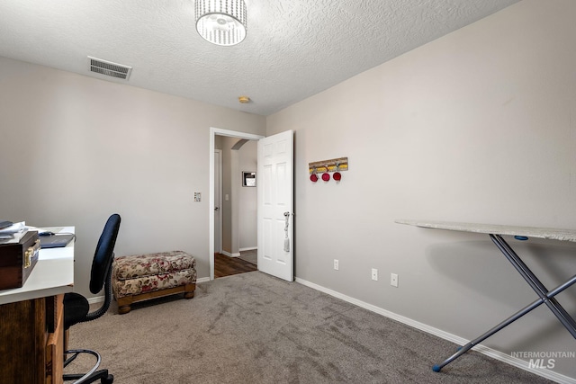 carpeted home office with visible vents, baseboards, and a textured ceiling