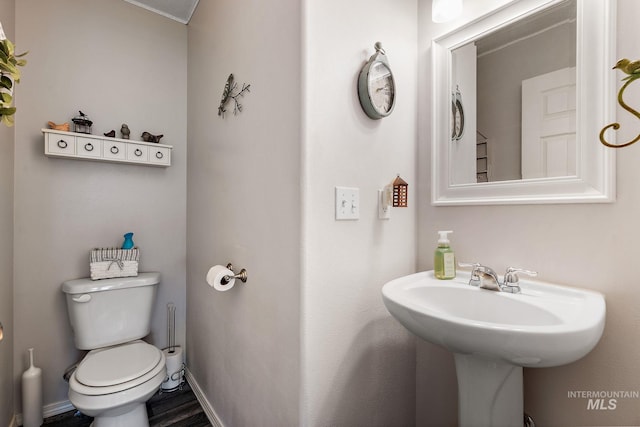 half bathroom featuring baseboards, toilet, and wood finished floors