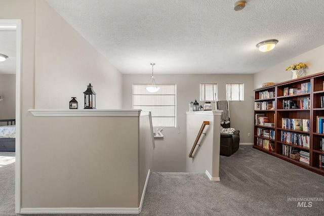 interior space featuring baseboards, an upstairs landing, carpet, and a textured ceiling