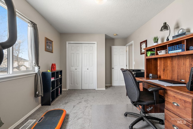 carpeted office space featuring baseboards and a textured ceiling