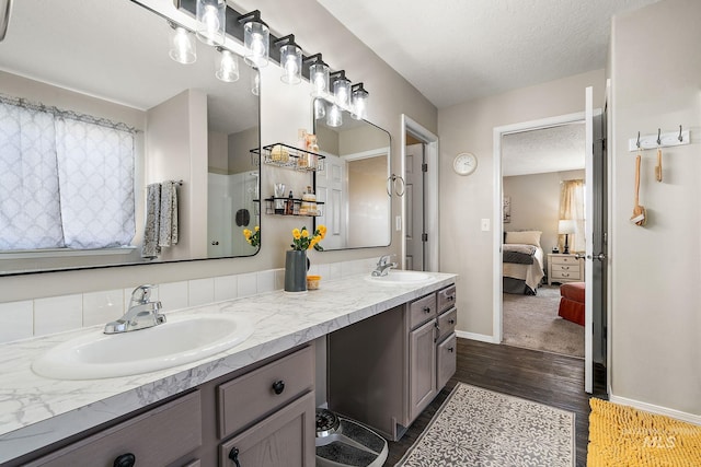 ensuite bathroom with a textured ceiling, wood finished floors, ensuite bathroom, and a sink