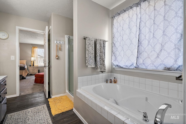 bathroom featuring a garden tub, a textured ceiling, wood finished floors, ensuite bath, and a shower stall