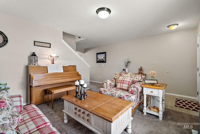 carpeted living area with baseboards, a textured ceiling, and stairs