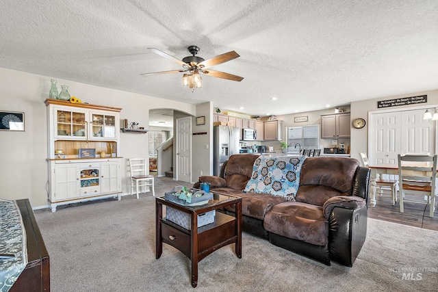 living room with baseboards, stairway, carpet flooring, arched walkways, and a ceiling fan