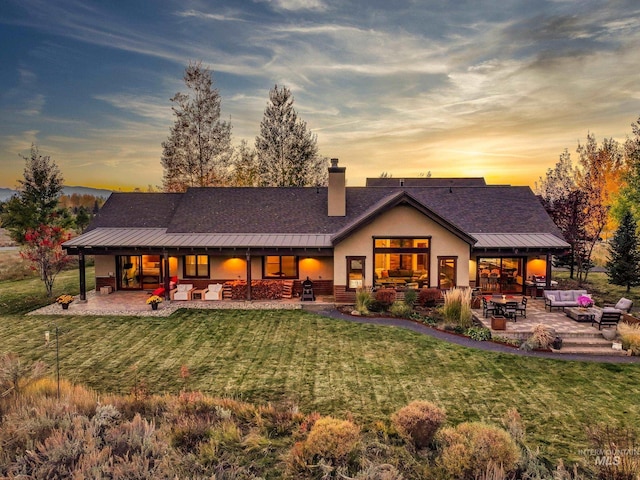 306 Otter Pond Ln, Mccall, ID 83638 - back of property at dusk with an outdoor living space, a yard, a patio, and a standing seam roof