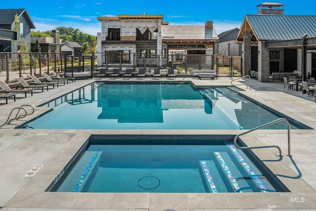 community pool featuring a patio, fence, and a hot tub