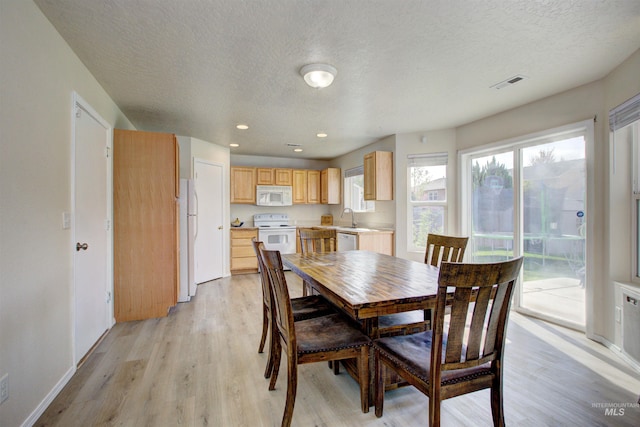 dining room with baseboards, visible vents, a textured ceiling, and light wood finished floors