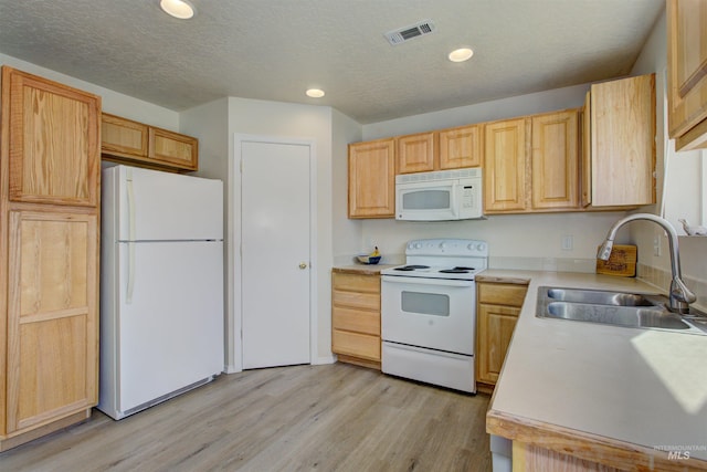 kitchen with white appliances, light countertops, light wood-style flooring, and a sink
