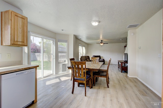 dining room featuring a ceiling fan, a healthy amount of sunlight, light wood-style floors, and a textured ceiling
