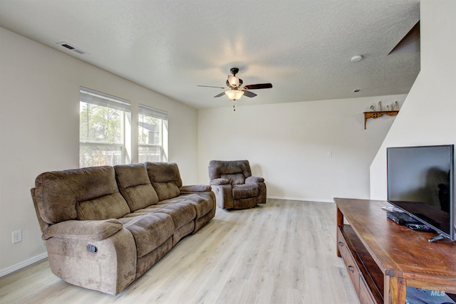 living area featuring baseboards, visible vents, a ceiling fan, and light wood finished floors