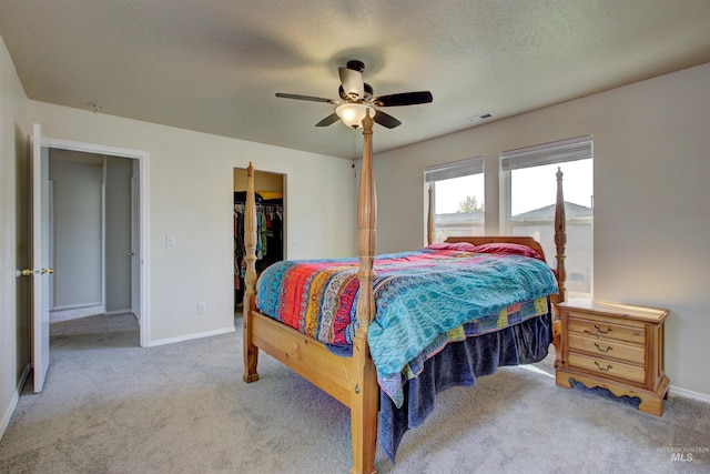 carpeted bedroom with a textured ceiling, ceiling fan, visible vents, baseboards, and a spacious closet