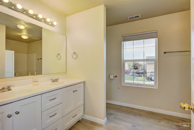 bathroom with visible vents, wood finished floors, double vanity, and a sink