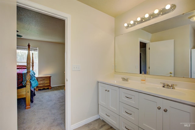 ensuite bathroom with baseboards, connected bathroom, double vanity, and a sink