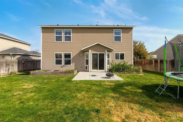 back of house featuring a fenced backyard, a fire pit, a patio area, and a trampoline