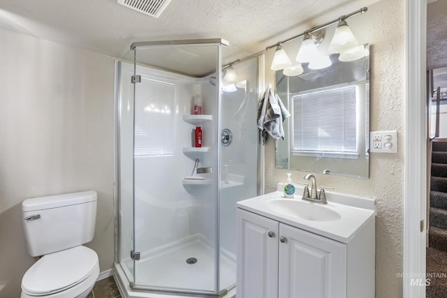 bathroom featuring visible vents, a textured wall, toilet, vanity, and a shower stall