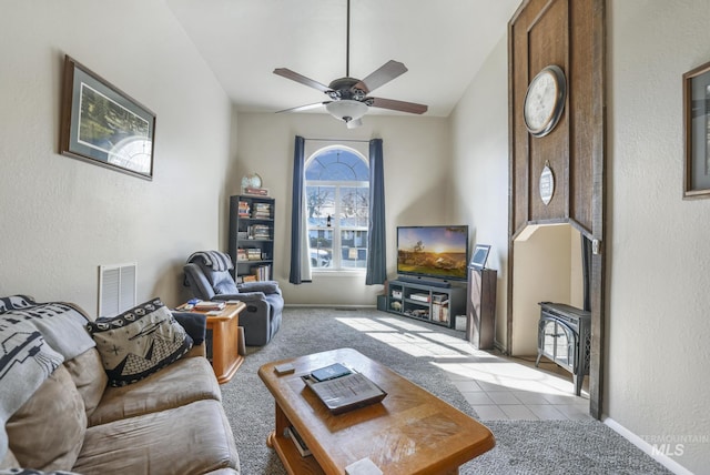 tiled living room featuring a ceiling fan, visible vents, vaulted ceiling, and baseboards