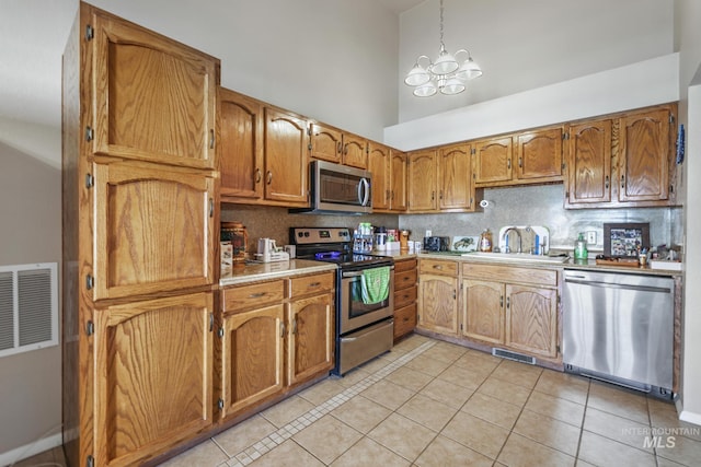 kitchen featuring a towering ceiling, visible vents, appliances with stainless steel finishes, and brown cabinets